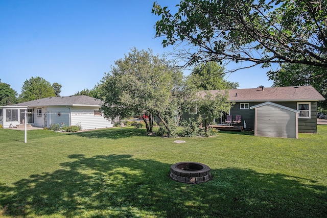 501 Central Ln, Luverne, MN 56156 - view of grassy yard with an outdoor fire pit, a wooden deck, a sunroom, and a shed