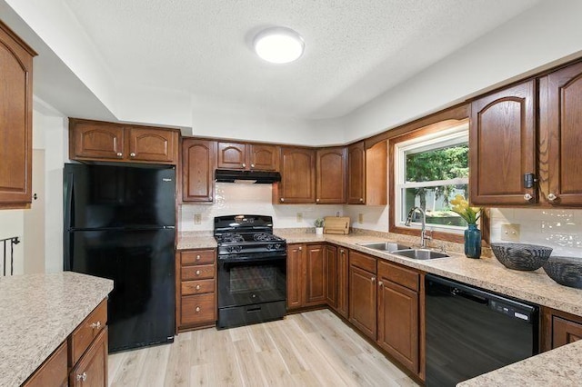 1821 Wilson Ave, Saint Paul, MN 55106 - kitchen featuring black appliances, under cabinet range hood, light wood-style floors, a textured ceiling, and decorative backsplash
