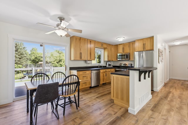 3205 Adair Ave NE, Buffalo, MN 55313 - kitchen featuring appliances with stainless steel finishes, dark countertops, ceiling fan, light wood-style floors, and a kitchen island