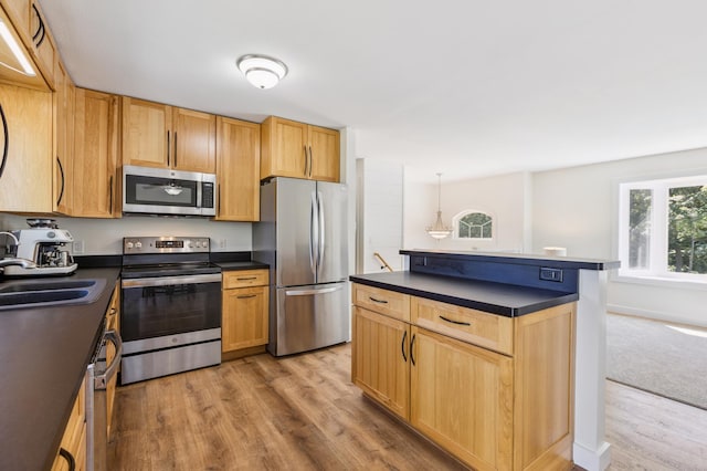 3205 Adair Ave NE, Buffalo, MN 55313 - kitchen featuring appliances with stainless steel finishes, dark countertops, light wood-type flooring, and a kitchen island