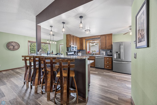 3402 Par St N, Fargo, ND 58102 - kitchen with appliances with stainless steel finishes, backsplash, brown cabinetry, and wood finished floors