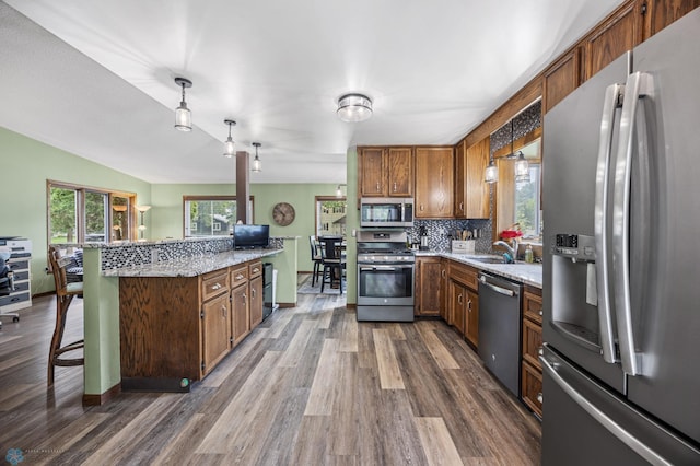 3402 Par St N, Fargo, ND 58102 - kitchen featuring appliances with stainless steel finishes, dark wood-type flooring, a kitchen bar, tasteful backsplash, and lofted ceiling