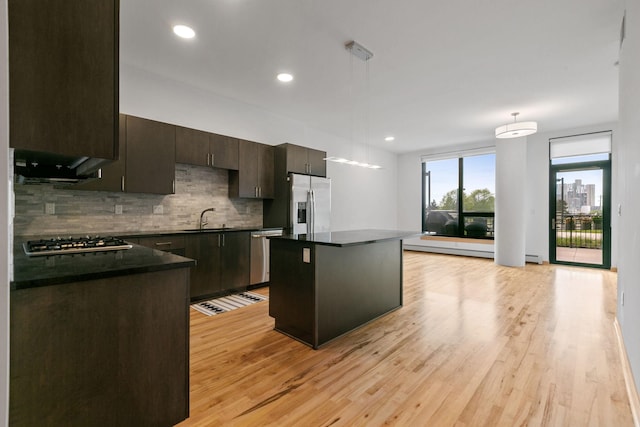 1240 2nd St Unit 225, Minneapolis, MN 55415 - kitchen with appliances with stainless steel finishes, dark countertops, decorative backsplash, a center island, and light wood-style floors