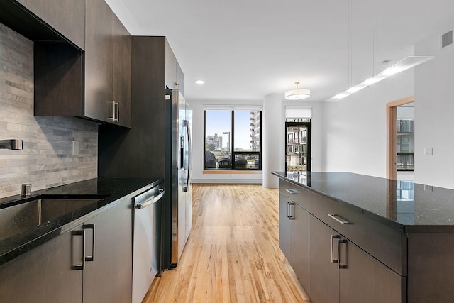 1240 2nd St Unit 225, Minneapolis, MN 55415 - kitchen featuring stainless steel appliances, light wood-type flooring, decorative backsplash, dark brown cabinetry, and a kitchen island