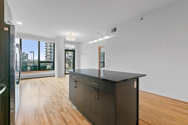 1240 2nd St Unit 225, Minneapolis, MN 55415 - kitchen featuring light wood finished floors, a kitchen island, freestanding refrigerator, and a city view