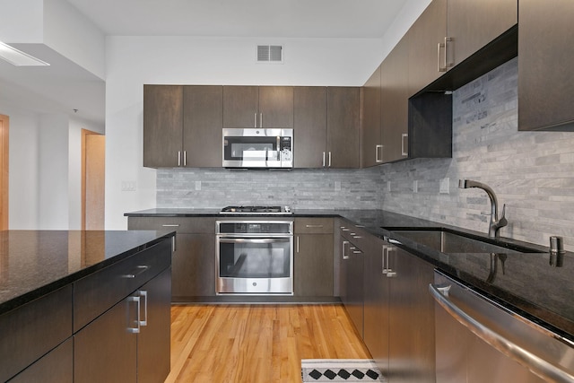 1240 2nd St Unit 225, Minneapolis, MN 55415 - kitchen featuring appliances with stainless steel finishes, dark stone counters, dark brown cabinetry, and decorative backsplash