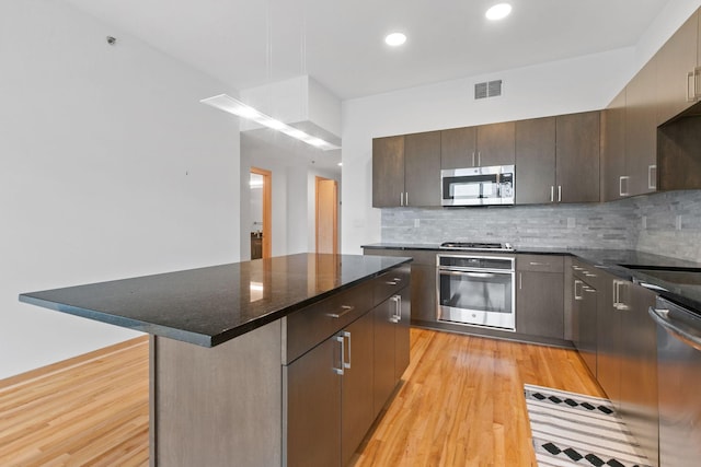 1240 2nd St Unit 225, Minneapolis, MN 55415 - kitchen with stainless steel appliances, light wood-style floors, a kitchen island, decorative backsplash, and recessed lighting