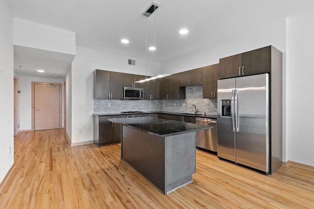 1240 2nd St Unit 225, Minneapolis, MN 55415 - kitchen with appliances with stainless steel finishes, dark brown cabinetry, a center island, tasteful backsplash, and light wood-type flooring