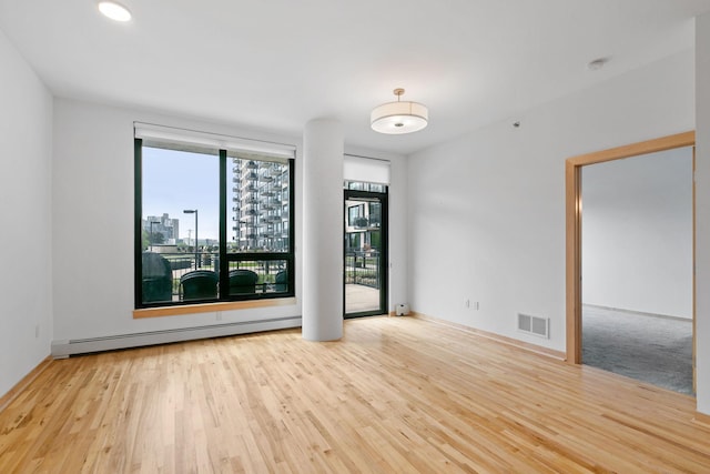 1240 2nd St Unit 225, Minneapolis, MN 55415 - unfurnished room featuring a baseboard heating unit, wood finished floors, a city view, and a smoke detector