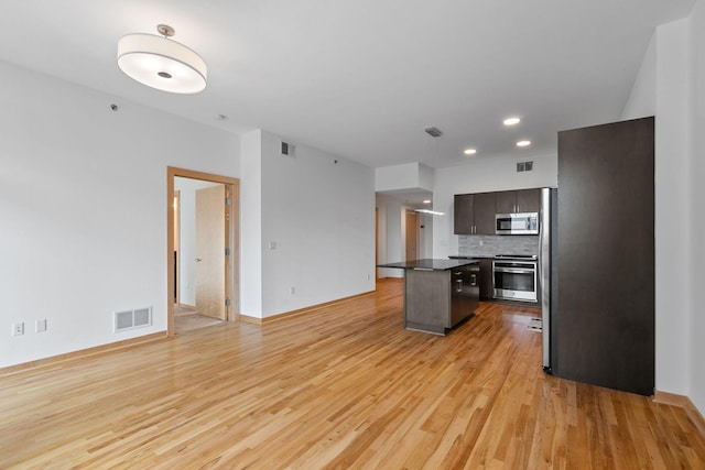 1240 2nd St Unit 225, Minneapolis, MN 55415 - kitchen featuring stainless steel microwave, stove, light wood-style flooring, a kitchen island, and dark countertops