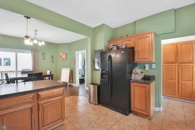 51 6th Ave N, Fargo, ND 58102 - kitchen with black fridge with ice dispenser, dark countertops, light tile patterned floors, hanging light fixtures, and a chandelier