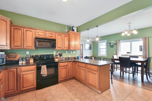 51 6th Ave N, Fargo, ND 58102 - kitchen with black appliances, dark countertops, a chandelier, and light tile patterned flooring