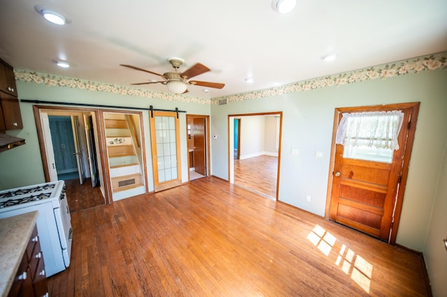415 Minnesota Ave S, Oronoco, MN 55960 - unfurnished living room with wood finished floors, ceiling fan, a barn door, and recessed lighting