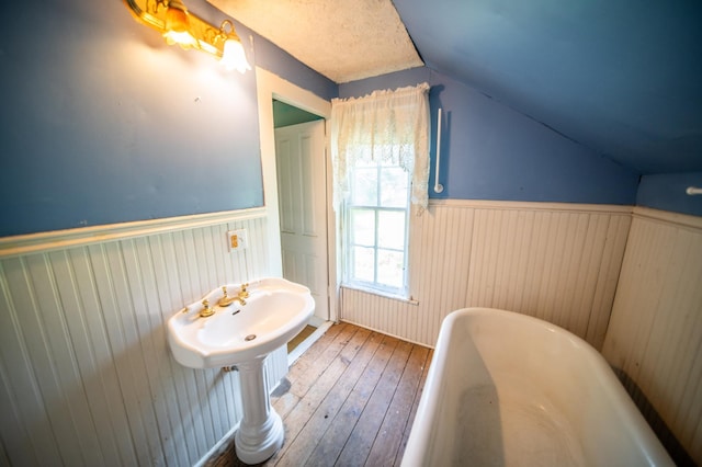 415 Minnesota Ave S, Oronoco, MN 55960 - bathroom featuring a freestanding bath, vaulted ceiling, wainscoting, and hardwood / wood-style flooring