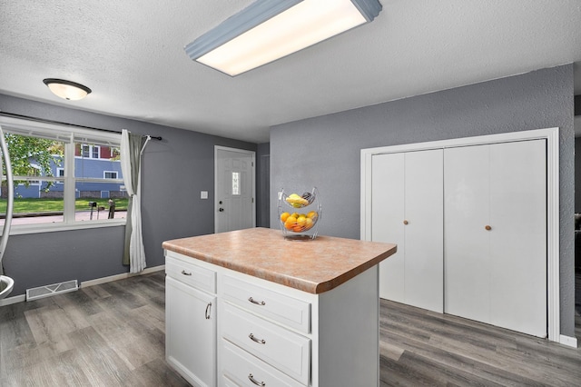 400 Mill St, Loyal, WI 54446 - kitchen with a textured ceiling, wood finished floors, white cabinetry, a kitchen island, and light countertops