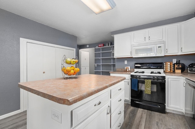 400 Mill St, Loyal, WI 54446 - kitchen featuring white microwave, gas range oven, wood finished floors, white cabinets, and a textured wall