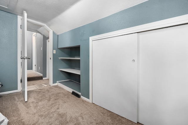 400 Mill St, Loyal, WI 54446 - unfurnished bedroom with carpet floors, vaulted ceiling, a closet, and a textured ceiling