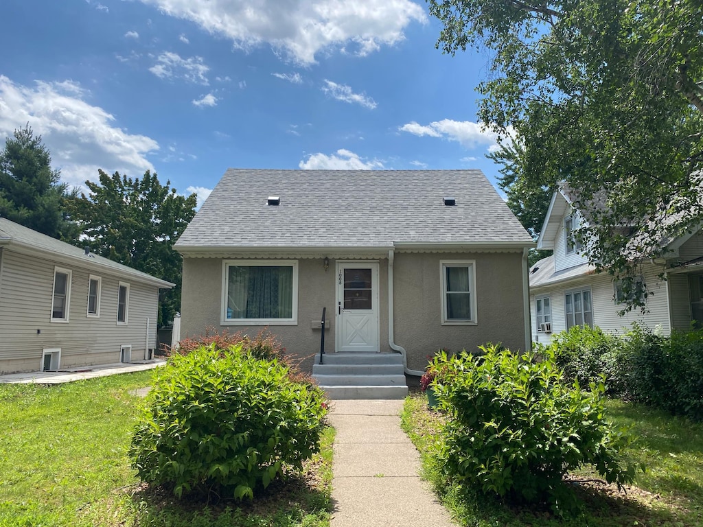 1008 Hawthorne Ave E, Saint Paul, MN 55106 - bungalow with stucco siding, a shingled roof, and a front yard