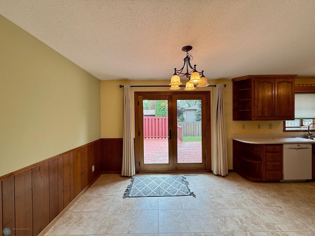 2602 Eastgate Dr S, Fargo, ND 58103 - entryway featuring a chandelier, a textured ceiling, wainscoting, french doors, and wooden walls