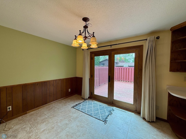 2602 Eastgate Dr S, Fargo, ND 58103 - entryway with a chandelier, french doors, a textured ceiling, wainscoting, and wood walls