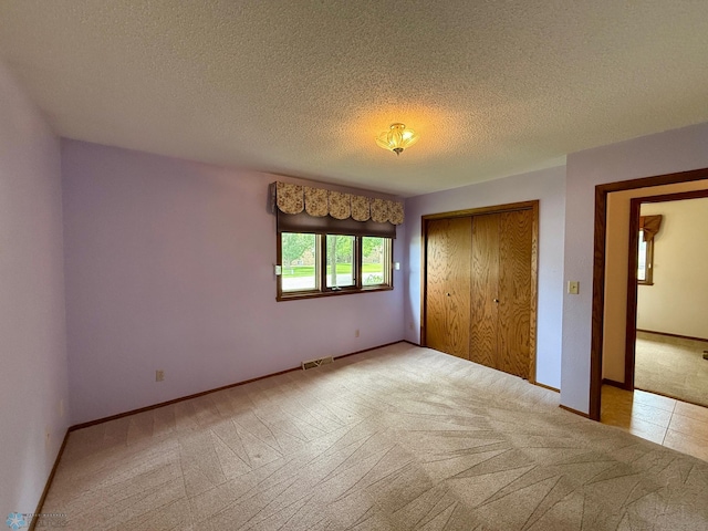 2602 Eastgate Dr S, Fargo, ND 58103 - unfurnished bedroom with light colored carpet, a closet, and a textured ceiling