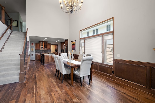4407 Curve Ave, Edina, MN 55424 - dining room featuring a chandelier, stairs, dark wood-style flooring, wainscoting, and a towering ceiling
