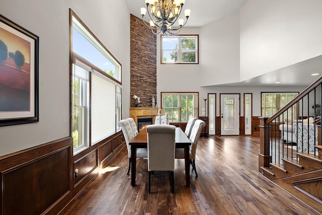 4407 Curve Ave, Edina, MN 55424 - dining space featuring a chandelier, a towering ceiling, dark wood-type flooring, a wainscoted wall, and a fireplace