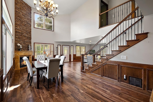 4407 Curve Ave, Edina, MN 55424 - dining space with a chandelier, a stone fireplace, a towering ceiling, stairway, and dark wood-style floors