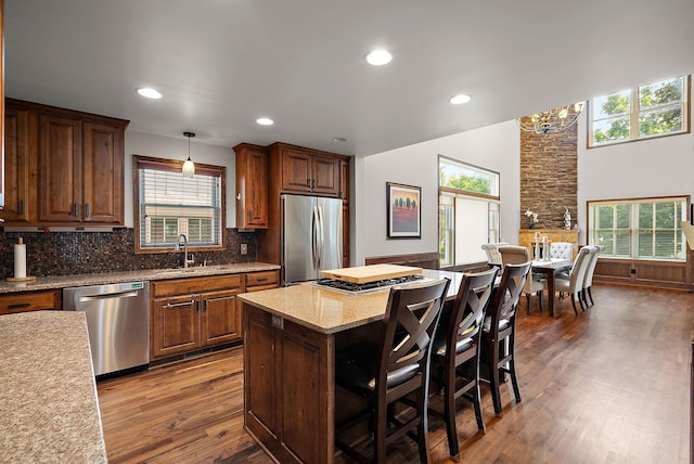 4407 Curve Ave, Edina, MN 55424 - kitchen featuring appliances with stainless steel finishes, wood finished floors, a kitchen breakfast bar, tasteful backsplash, and hanging light fixtures