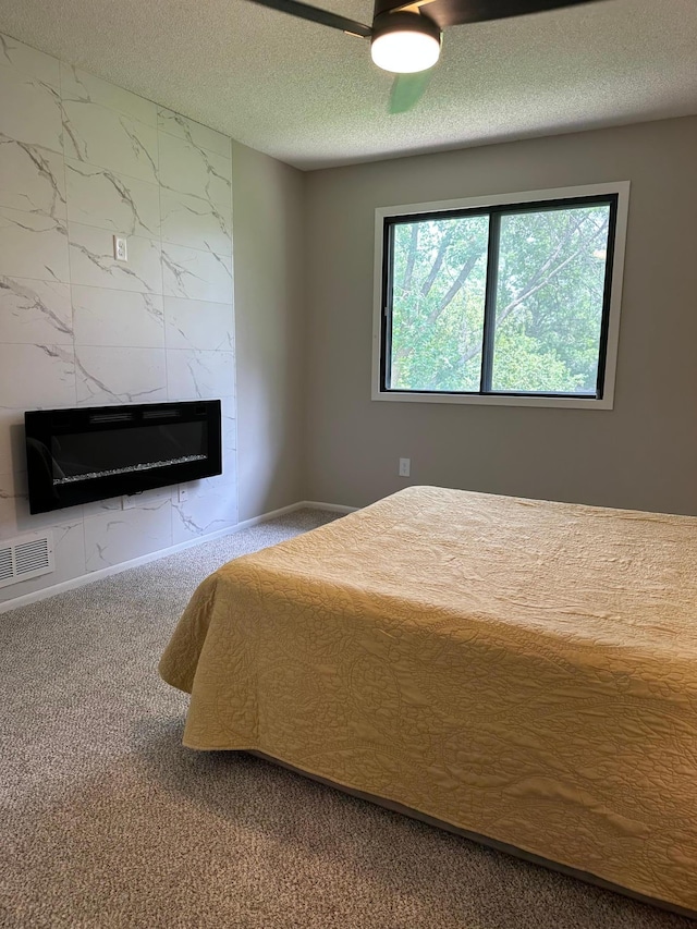 12619 Alder St NW, Coon Rapids, MN 55448 - carpeted bedroom featuring a premium fireplace, a textured ceiling, and ceiling fan