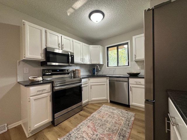 12619 Alder St NW, Coon Rapids, MN 55448 - kitchen featuring stainless steel appliances, light wood-type flooring, white cabinets, and a textured ceiling