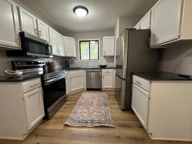 12619 Alder St NW, Coon Rapids, MN 55448 - kitchen featuring stainless steel appliances, white cabinets, light wood-type flooring, and a textured ceiling