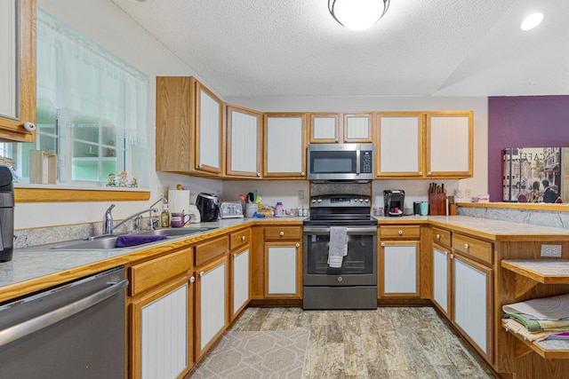 114 Oxford Path, Mankato, MN 56001 - kitchen with stainless steel appliances, light wood-style flooring, a textured ceiling, a peninsula, and light countertops