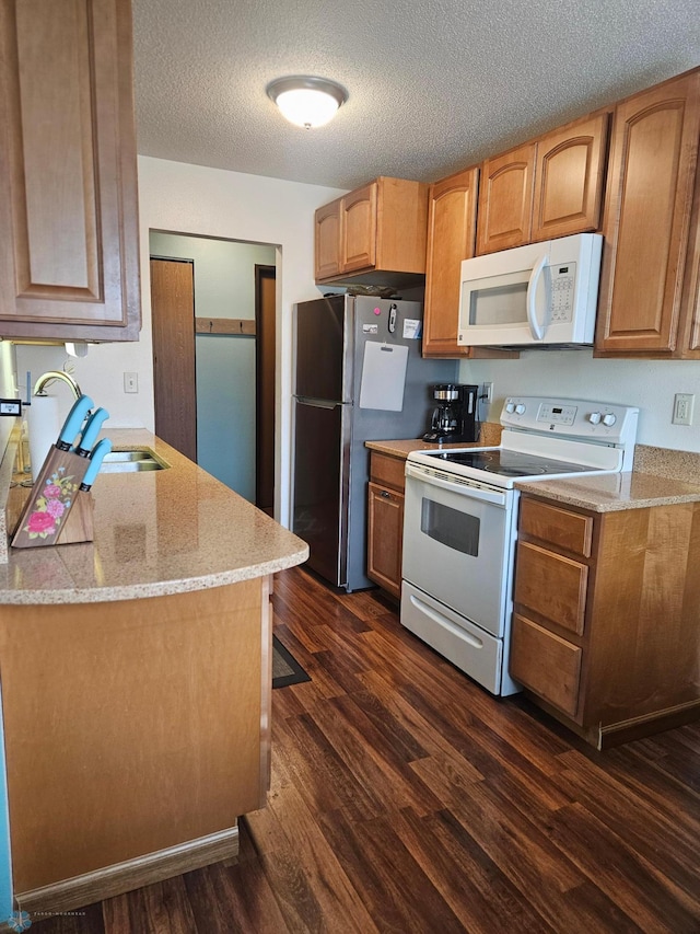 311 Prairiewood Cir S Unit 307, Fargo, ND 58103 - kitchen featuring white appliances, dark wood finished floors, a textured ceiling, light stone countertops, and brown cabinetry