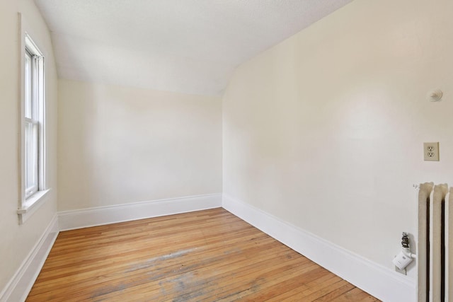 1108 16th Ave SE, Minneapolis, MN 55414 - spare room with lofted ceiling, light wood finished floors, and radiator heating unit