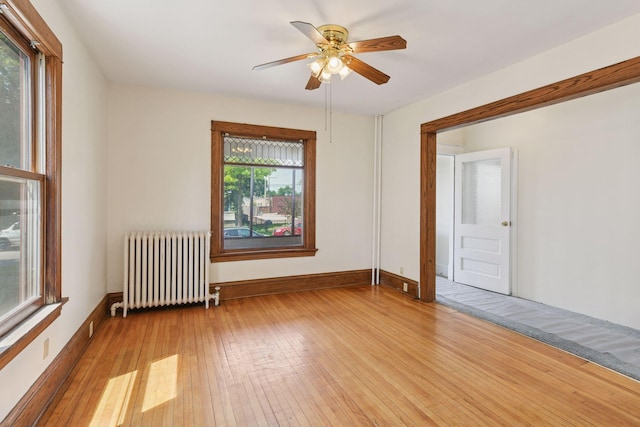1108 16th Ave SE, Minneapolis, MN 55414 - unfurnished room with radiator heating unit, light wood-type flooring, and ceiling fan