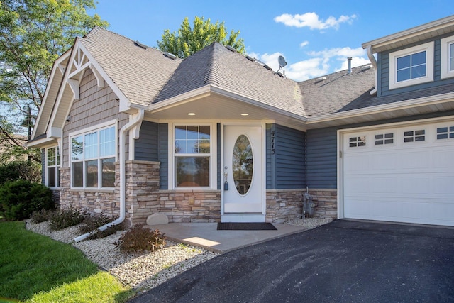4715 Wyngate Blvd, Forest Lake, MN 55025 - view of front of house featuring stone siding, roof with shingles, a garage, and asphalt driveway