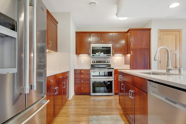 4715 Wyngate Blvd, Forest Lake, MN 55025 - kitchen with appliances with stainless steel finishes, light wood-style floors, light stone counters, and brown cabinetry