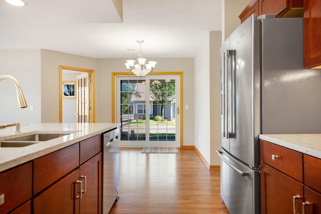 4715 Wyngate Blvd, Forest Lake, MN 55025 - kitchen with appliances with stainless steel finishes, light wood-type flooring, a chandelier, pendant lighting, and light stone countertops
