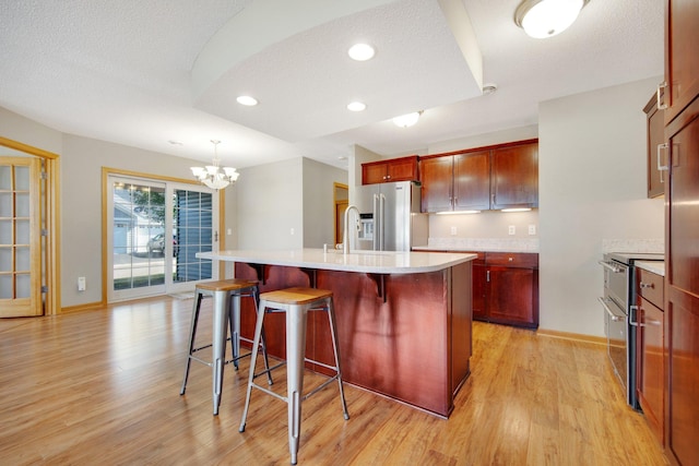 4715 Wyngate Blvd, Forest Lake, MN 55025 - kitchen with stainless steel appliances, a chandelier, light wood-style floors, light countertops, and a kitchen island with sink