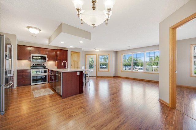 4715 Wyngate Blvd, Forest Lake, MN 55025 - kitchen featuring stainless steel appliances, open floor plan, light countertops, light wood finished floors, and a chandelier
