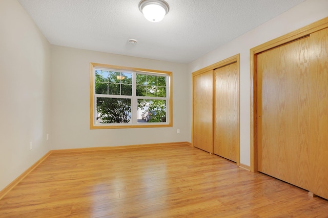 4715 Wyngate Blvd, Forest Lake, MN 55025 - unfurnished bedroom featuring multiple closets, light wood-style flooring, and a textured ceiling