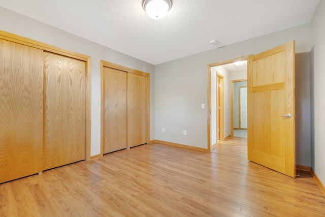 4715 Wyngate Blvd, Forest Lake, MN 55025 - unfurnished bedroom featuring two closets, light wood-type flooring, and a textured ceiling