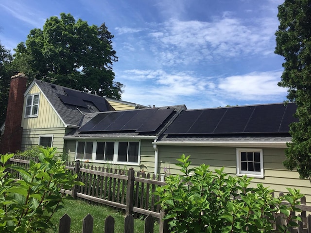 5505 Morgan Ave S, Minneapolis, MN 55419 - view of side of property featuring roof mounted solar panels, roof with shingles, a chimney, and a sunroom