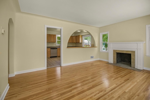 4700 Xerxes Ave N, Minneapolis, MN 55430 - unfurnished living room with light wood-style flooring, a tile fireplace, and arched walkways