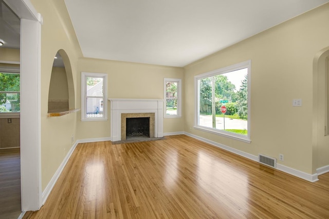 4700 Xerxes Ave N, Minneapolis, MN 55430 - unfurnished living room with light wood-type flooring, plenty of natural light, a tile fireplace, and arched walkways