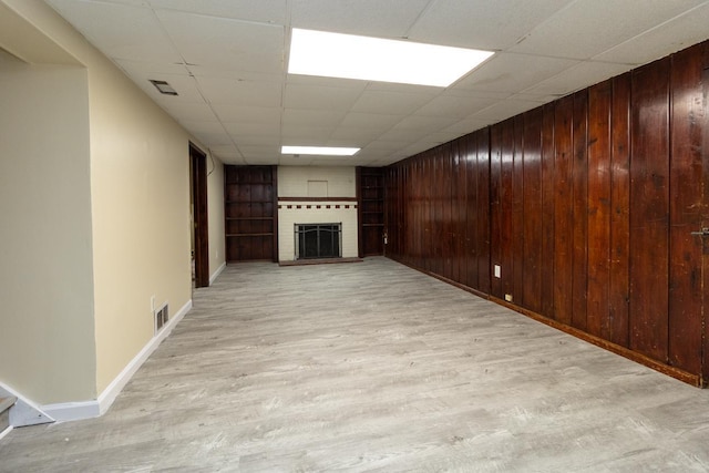 4700 Xerxes Ave N, Minneapolis, MN 55430 - unfurnished living room featuring light wood-style flooring, a brick fireplace, wooden walls, and a drop ceiling