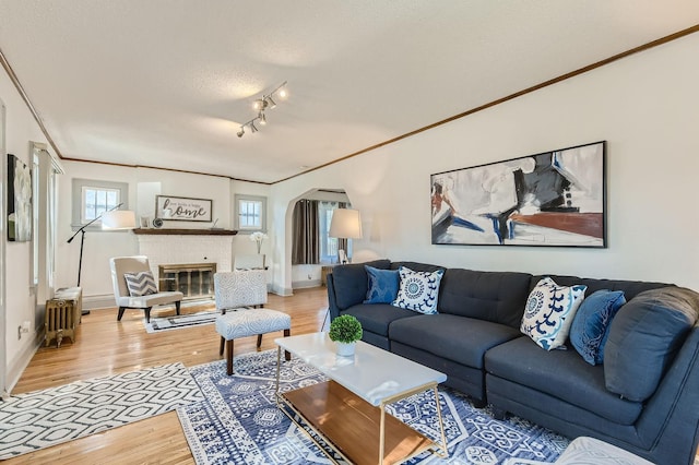 2810 Morgan Ave N, Minneapolis, MN 55411 - living room with light wood-type flooring, plenty of natural light, a textured ceiling, a brick fireplace, and ornamental molding