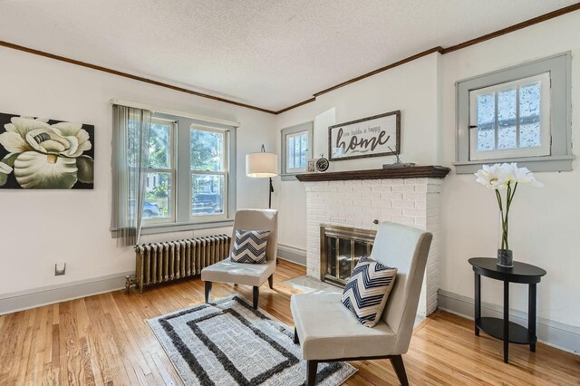2810 Morgan Ave N, Minneapolis, MN 55411 - living area featuring radiator heating unit, ornamental molding, hardwood / wood-style flooring, a textured ceiling, and a fireplace