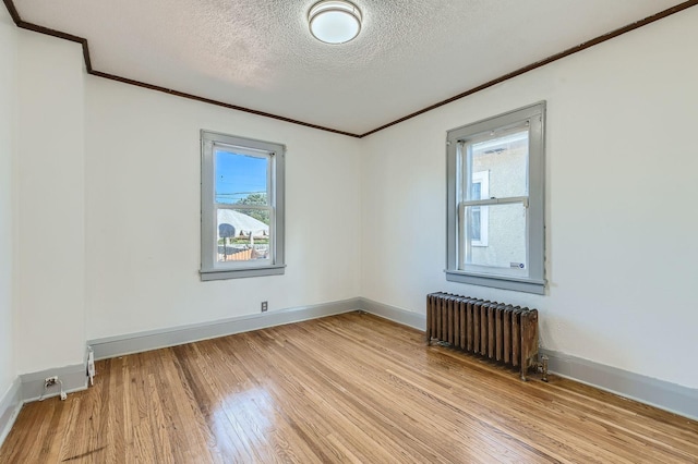2810 Morgan Ave N, Minneapolis, MN 55411 - empty room featuring radiator heating unit, crown molding, light wood-style floors, and a textured ceiling
